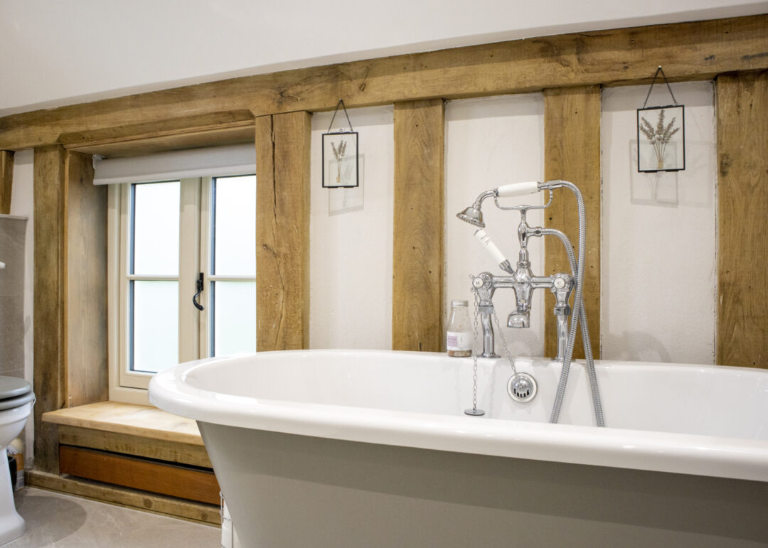 Oak beamed luxury bathroom with cute timber casement window with black handle and glazing bars